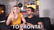 a man and a woman are sitting on a couch with the words to pronta written on the screen