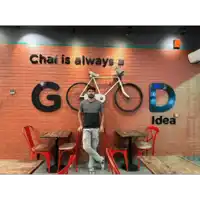 a man stands in front of a sign that says chai is always good idea