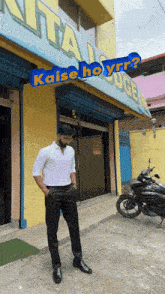 a man standing in front of a building that says ' kaise ho yrr '