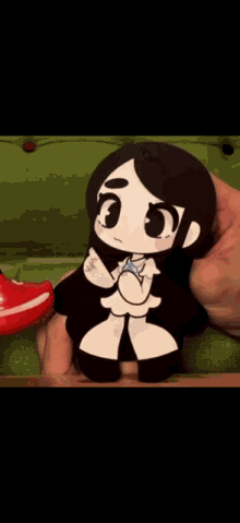 a person is holding a black and white cartoon character on a green couch