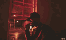 a man smoking a cigarette in a dark room with a vevo logo on the bottom