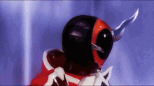 a man in a red and black superhero costume with a knife in his mouth