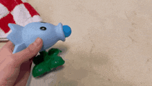a person is holding a blue and green toy fish