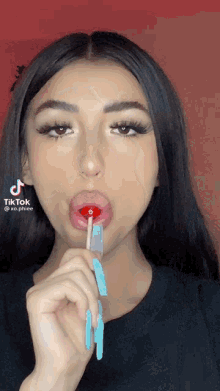 a woman is holding a lollipop in her mouth with a tiktok logo on the bottom right