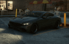 a black car is parked in a parking lot in front of a building with graffiti on it