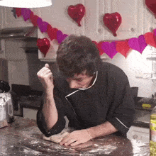 a man in a chef 's jacket is kneading dough