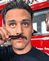 a man with a mustache is holding a comb to his nose