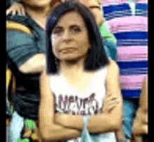 a woman with her arms crossed is standing in front of a group of people .