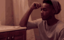 a man in a gray shirt is brushing his teeth in a bathroom sink