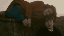 a boy and a girl are laying on top of a rock .