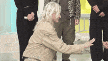 a woman in a tan jacket is kneeling down