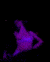 a blurry picture of a woman singing into a microphone in purple lights .