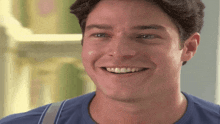 a young man wearing a blue shirt and suspenders smiles for the camera
