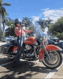 a woman is standing next to a red motorcycle in a parking lot .
