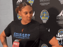 a woman wearing a chicago basketball shirt stands in front of a wall