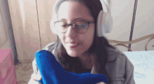 a woman wearing headphones and glasses is holding a blue object