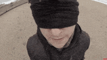 a man wearing a blindfold is standing on a sandy beach