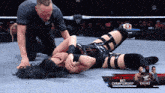 a woman is laying on the ground in a wrestling ring with a triple threat nxt championship banner