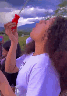 a woman blowing soap bubbles in a field with mountains in the background .