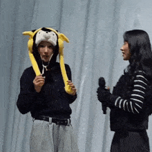 a woman wearing a stuffed animal hat talks to another woman