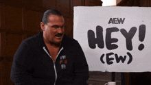 a man stands in front of a sign that says hey ( ew )