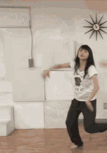 a woman is dancing in a room in front of a clock .