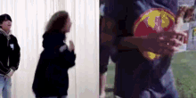 a man and a woman are standing next to each other in a room . the man is wearing a superman shirt .