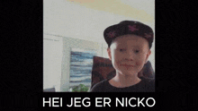 a young boy wearing a hat and a black shirt is smiling and looking at the camera .