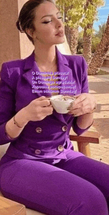 a woman in a purple suit is drinking from a white cup
