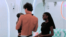 a man without a shirt is standing next to two women in a room