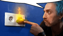 a man with blue hair is pointing at an electrical outlet