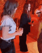 two women are dancing in a club and one is holding a drink .
