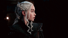 a woman with blonde hair is wearing a braided ponytail and a black jacket .