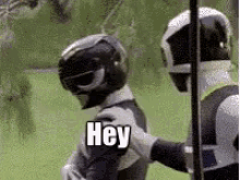 two power rangers are standing next to each other and one of them is holding the other 's shoulder .