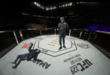 a man in a hoodie stands on a ufc 229 ring