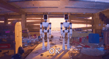 two robots are standing next to each other in a room with the word ok on the bottom right