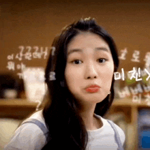 a close up of a woman making a funny face in front of a chalkboard with numbers written on it .