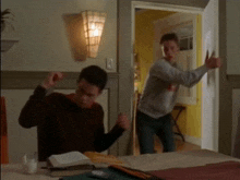 two men are dancing in a bedroom and one is holding a piece of paper