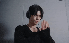 a young man wearing headphones and a necklace is standing in a dark room .