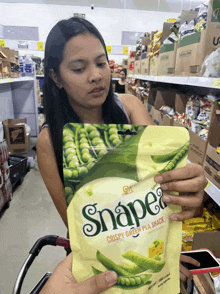a woman holds a bag of snape crispy green pea snacks