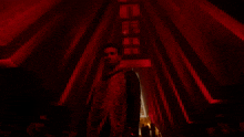 a man stands in a dark room with a red light behind him