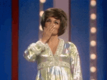 a woman in a green dress is covering her mouth with her hand .