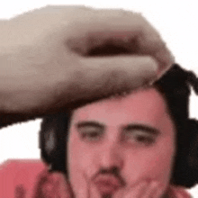 a person is putting their hand on a man 's forehead .