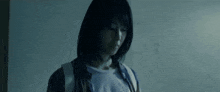 a woman with short hair is standing in a dark room looking down .