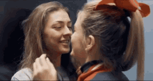 two women are kissing each other and one has a red bow in her hair .