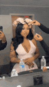 a woman in a pink dress is getting her makeup done in front of a mirror