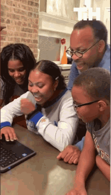 a group of people are looking at a laptop with the letter t on top