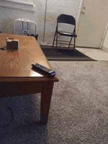 a remote sits on a wooden table next to a chair