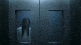 a woman in a white shirt is standing in a dark room