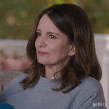 a woman sitting on a couch with a netflix logo in the corner of her face